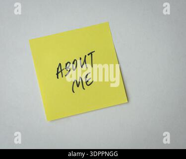 About Me note or message on stick on yellow paper. Isolated on white surface. Stock Photo