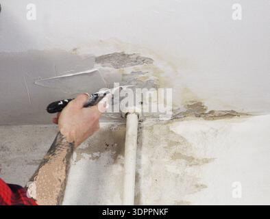 Master man applying putty plaster to the ceiling close-up. Stock Photo