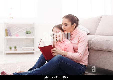 Mother and Daughter Reading Together on the Floor at Home During a Sunny Day Stock Photo