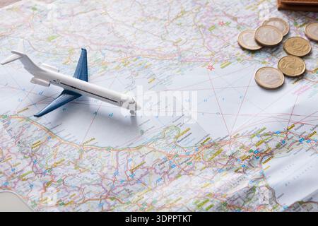 Model Airplane Placed on a Travel Map With Coins Scattered in a Planning Space Stock Photo