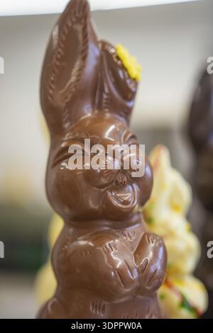 A brown chocolate bunny with a yellow flower on his ear, smiling happily, Easter production of regional products, Haselstaller Hof, Gechingen, Calw di Stock Photo