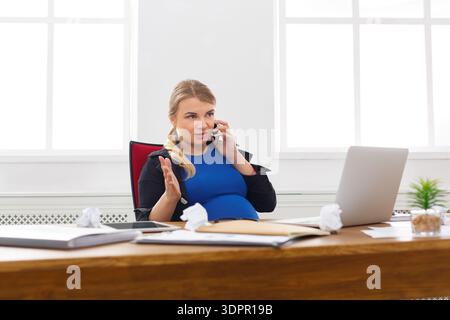 Pregnant Woman Talking on the Phone in an Office During the Day Stock Photo