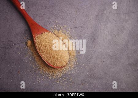 Brown sugar on a wooden spoon on a gray surface Stock Photo