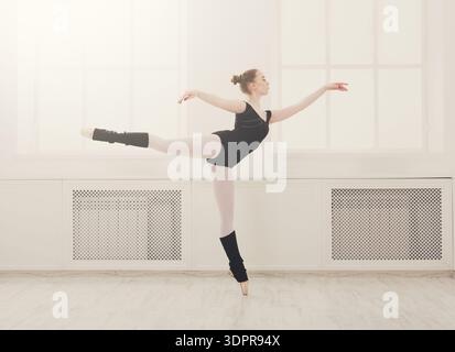 Ballet Dancer Performs En Pointe in Studio With Bright Windows and Wooden Floor Stock Photo