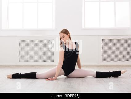Dancer Performs a Split in a Bright Studio With Large Windows During a Dance Rehearsal Stock Photo