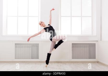 Dancer Practices Ballet in a Bright Studio With Large Windows and Wooden Floor Stock Photo
