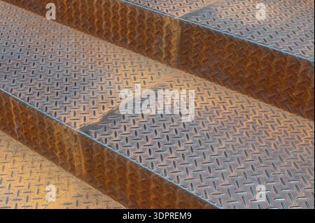 Close up of rusty metal diamond plate stairs in industrial area Stock Photo
