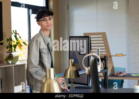 Man working on digital tablet beside curved monitor and gold desk lamp in studio Stock Photo