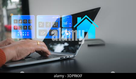 Close up of a woman hand using a laptop to manage smart home automation systems with a digital dashboard interface showing energy, security, and clima Stock Photo