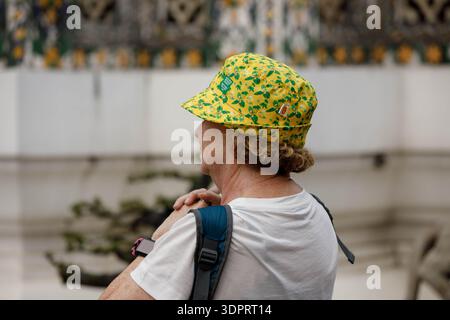 BANGKOK, THAILAND-JAN 21, 2026: Senior woman backpacker exploring Wat Thai, side profile Stock Photo