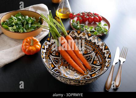 Vegetables in colorful ceramic plates. Healthy eating. Patterned bowl on black background. Modern porcelain tableware. Food and traditional cuisine Stock Photo
