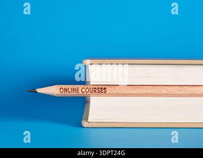 Enrolling to online courses concept. Wooden pencil reading online courses pushing through a book with a blue background, representing e learning and r Stock Photo