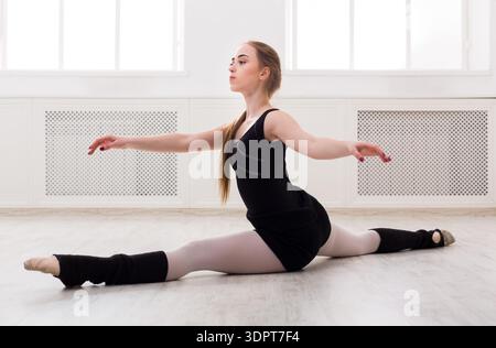 Dancer Practices a Split on a Wooden Floor in a Bright Studio During Daytime Stock Photo