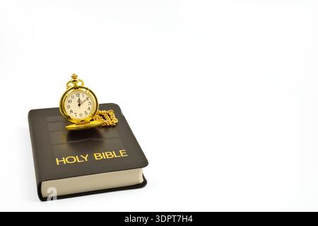 Pocket watch on a black leather Holy Bible with white background. Copy space above and to the right side. Stock Photo
