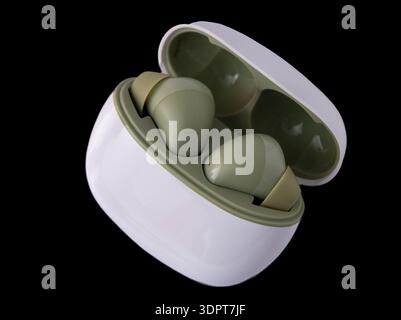 Wireless headphones isolated on black background. Wireless, headphone in charging box. Stock Photo