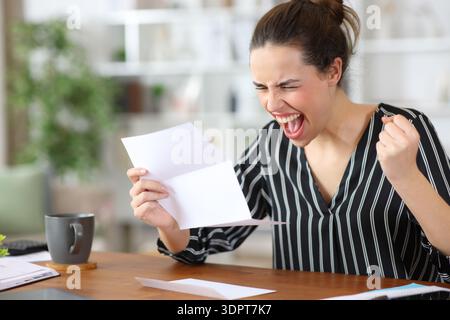 Excited self employed celebrating success holding letter working at home Stock Photo