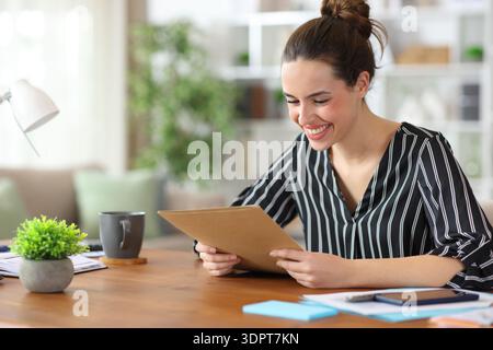 Happy self employed reading paper documents working at home Stock Photo