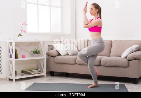 Woman Practicing Yoga at Home on a Mat in Living Room During Daytime Stock Photo