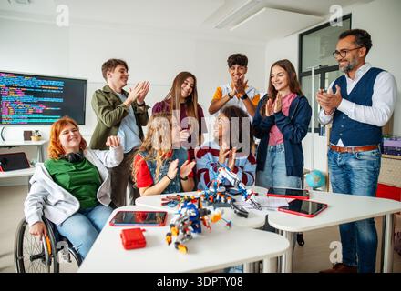Group of high school students celebrating successful experiment with robotic hand. Stock Photo