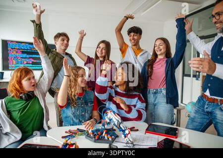 Group of high school students celebrating successful experiment with robotic hand. Stock Photo