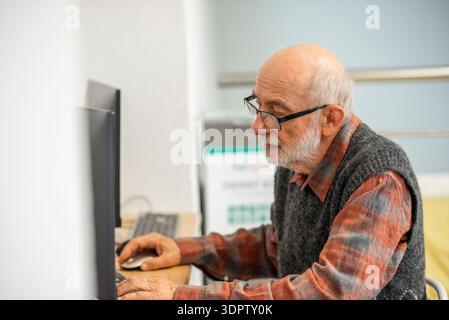 Senior man working on computer at desk. Stock Photo