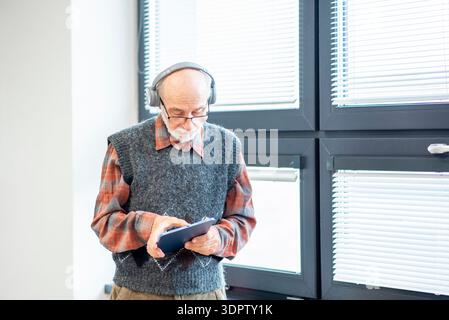 Senior man using tablet and headphones. Stock Photo