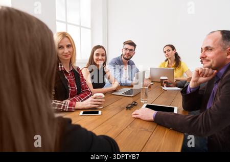 Group of People in a Meeting Discussing Ideas and Sharing Information in a Bright Room Stock Photo