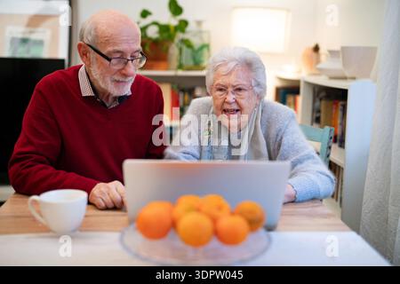Loving elderly couple makingn online reservation, using laptop. Stock Photo
