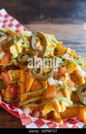 Nachos loaded with cheese, guacamole, jalapenos, and salsa Stock Photo