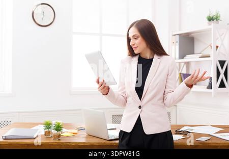Professional Woman Using Tablet While Standing at Desk in Office Space During Daytime Stock Photo