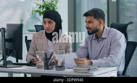 Two muslim business team in office working Islamic group Indian co-workers Arabian colleagues work with computer online startup success corporate Stock Photo