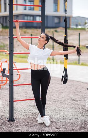 Athletic woman is training at an outdoor gym in a fitness park in the ...