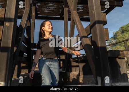 Young woman enjoying sunlight outdoors in wooden structure Stock Photo
