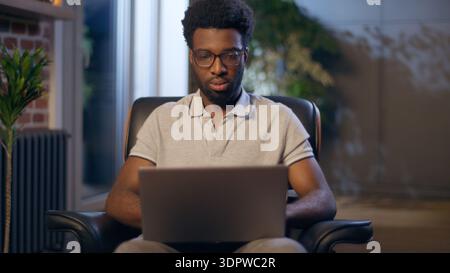 African American business man businessman in eyeglasses overwork tired in night office overtime working computer online exhausted guy male take off Stock Photo