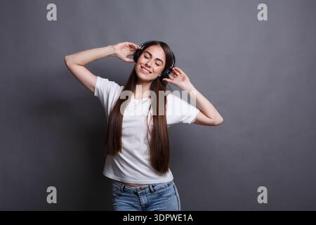 Young Woman Enjoys Music While Wearing Headphones in a Studio Setting Stock Photo