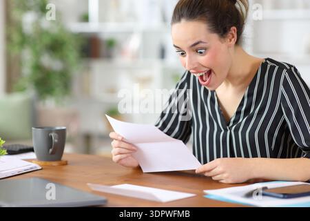 Excited self employed reading good news in letter working at home Stock Photo