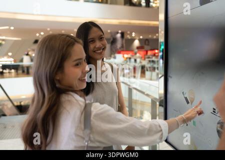Friends using interactive screen for shopping mall navigation Stock Photo
