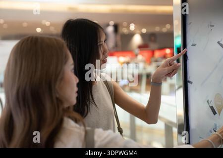 Women using interactive digital kiosk at shopping mall Stock Photo