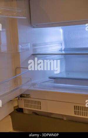 Empty refrigerator interior with open door, clean shelves, and bright cold lighting. Minimal household appliance background showing food storage space Stock Photo