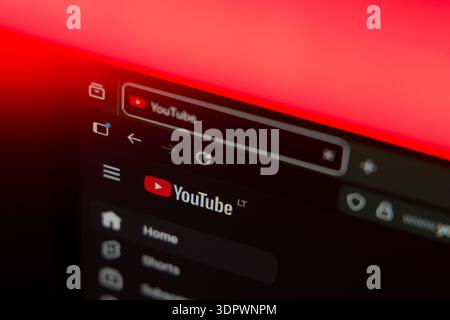 Close up of a web browser displaying the YouTube logo and home menu on a dark interface with a vibrant red lighting effect, representing online video Stock Photo