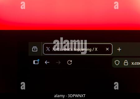 Close up of a web browser tab for X social media platform formerly known as Twitter on a black screen with a vibrant red light background, representin Stock Photo