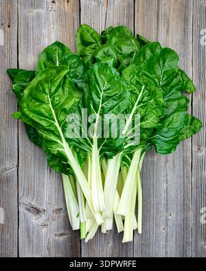 Swiss chard leaves with white stems arranged on wooden background. Fresh organic leafy greens top view Stock Photo