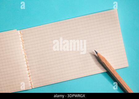 Top view of open graph paper notebook and pencil, simple stationery composition symbolizing creativity, organization, notes, and education. Copy space Stock Photo