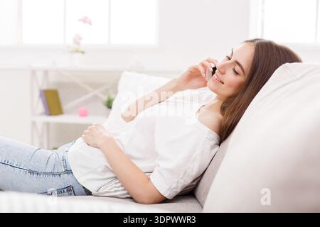 Young Woman Talking on the Phone While Sitting on a Couch in a Bright Room Stock Photo