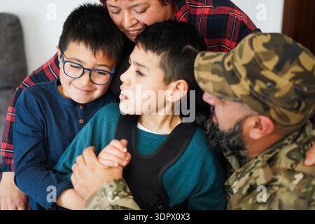 Man soldier hugging his family after returning from military service at home - Family moments, disability and war concept Stock Photo