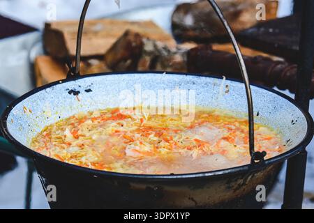 Cabbage soup or stew cooking in a big pot on the open fire, close up Stock Photo