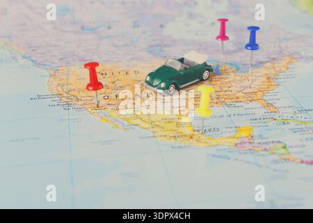 Small Green Car Model on a Map of the Southern United States With Colorful Push Pins Set in Place Stock Photo