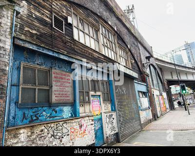Manchester, UK - January 24, 2026: Worn blue J.E. Gordon Ltd shopfront with peeling wood and graffiti along a Manchester street in the UK. Stock Photo