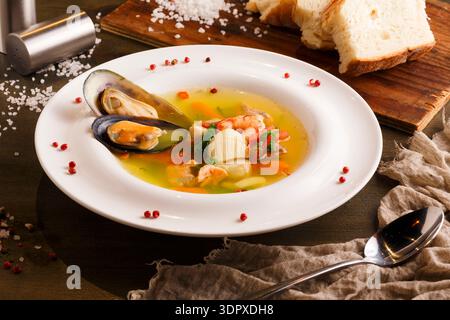 Seafood Soup on a White Plate Served With Bread on a Wooden Table Stock Photo