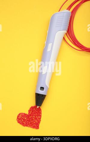 Red heart drawn by 3d pen on yellow background. Top view Stock Photo